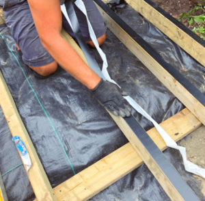 man installing Trex Protect tape on joists